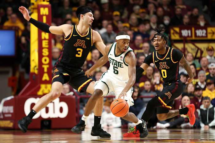 Feb 6, 2024; Minneapolis, Minnesota, USA; Michigan State Spartans guard Tre Holloman (5) dribbles as Minnesota Golden Gophers forward Dawson Garcia (3) and guard Elijah Hawkins (0) defend during the first half at Williams Arena.